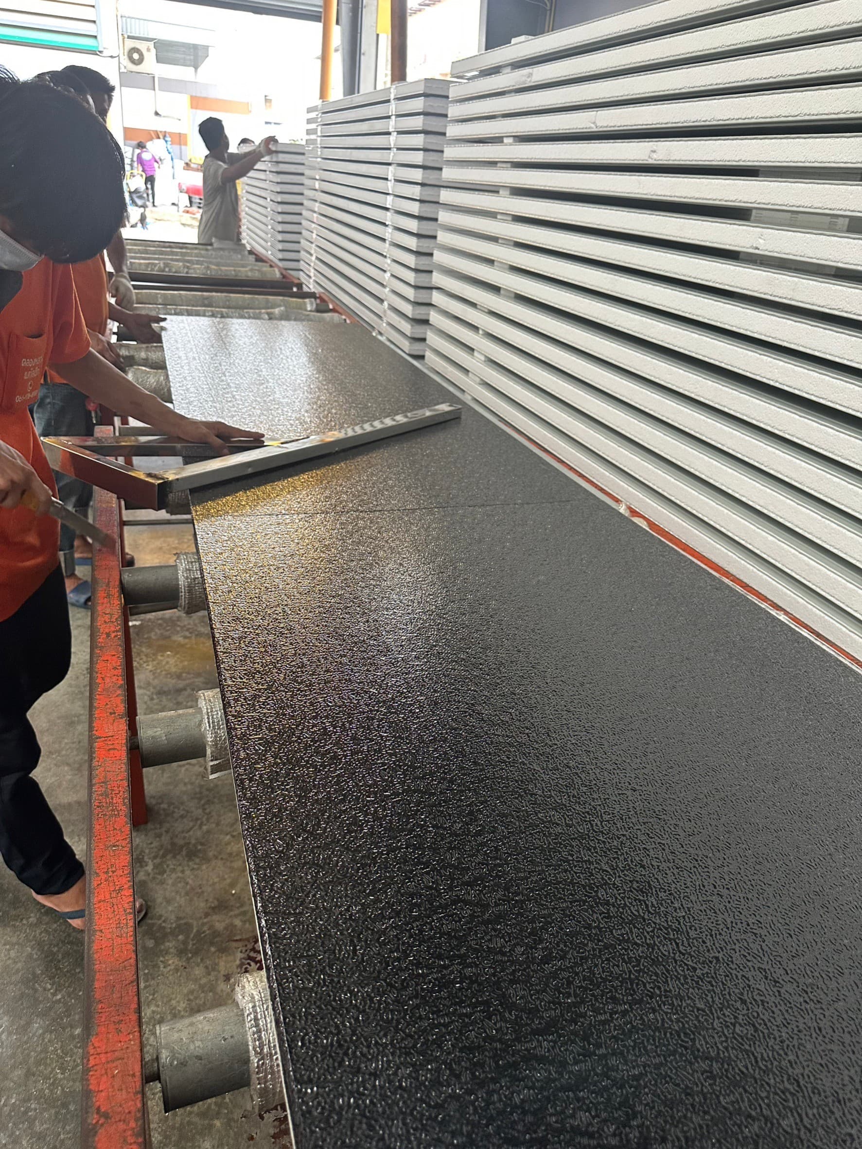 Workers finishing a black textured panel at the line