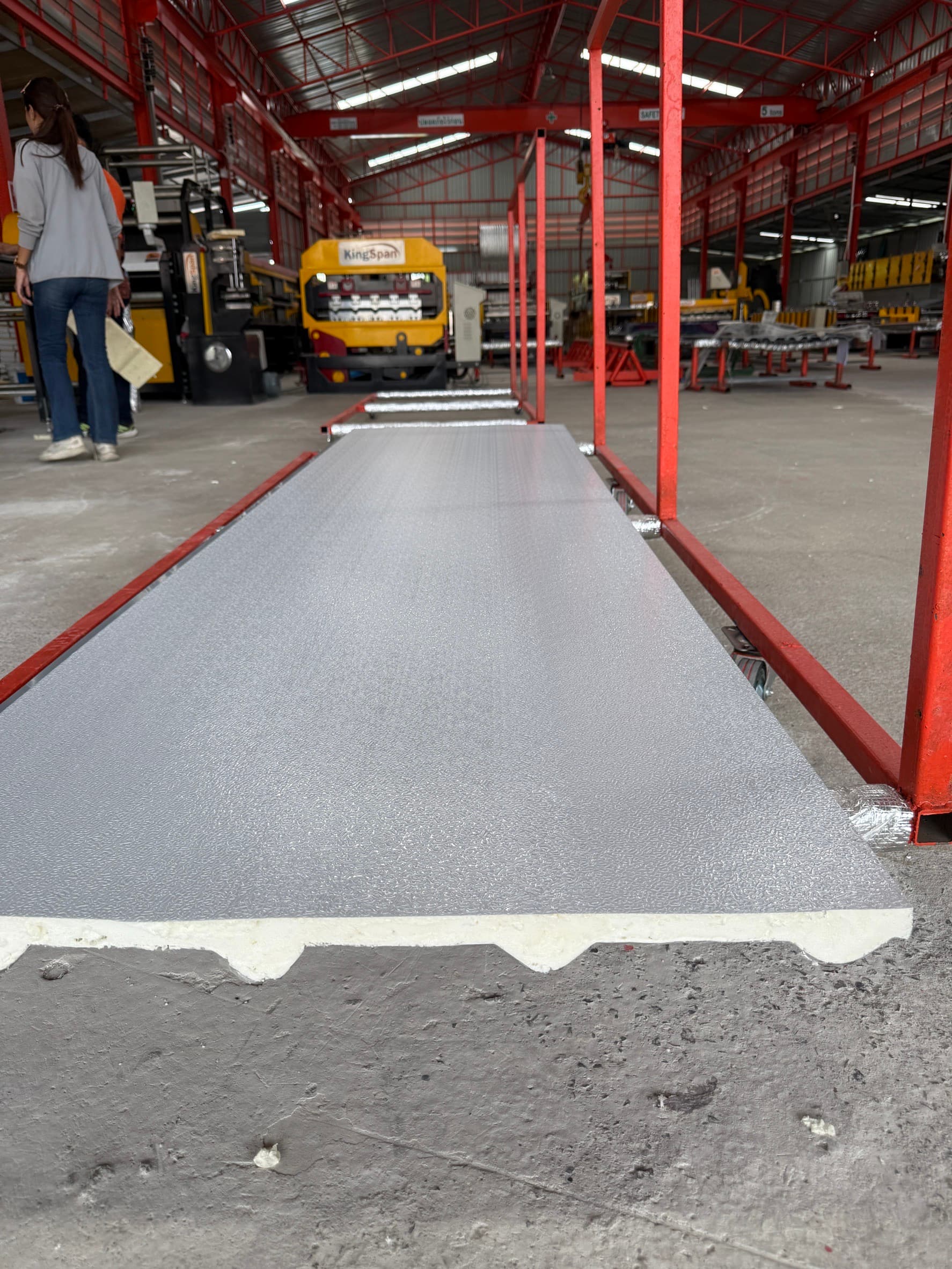 Long silver panel resting on a red production frame