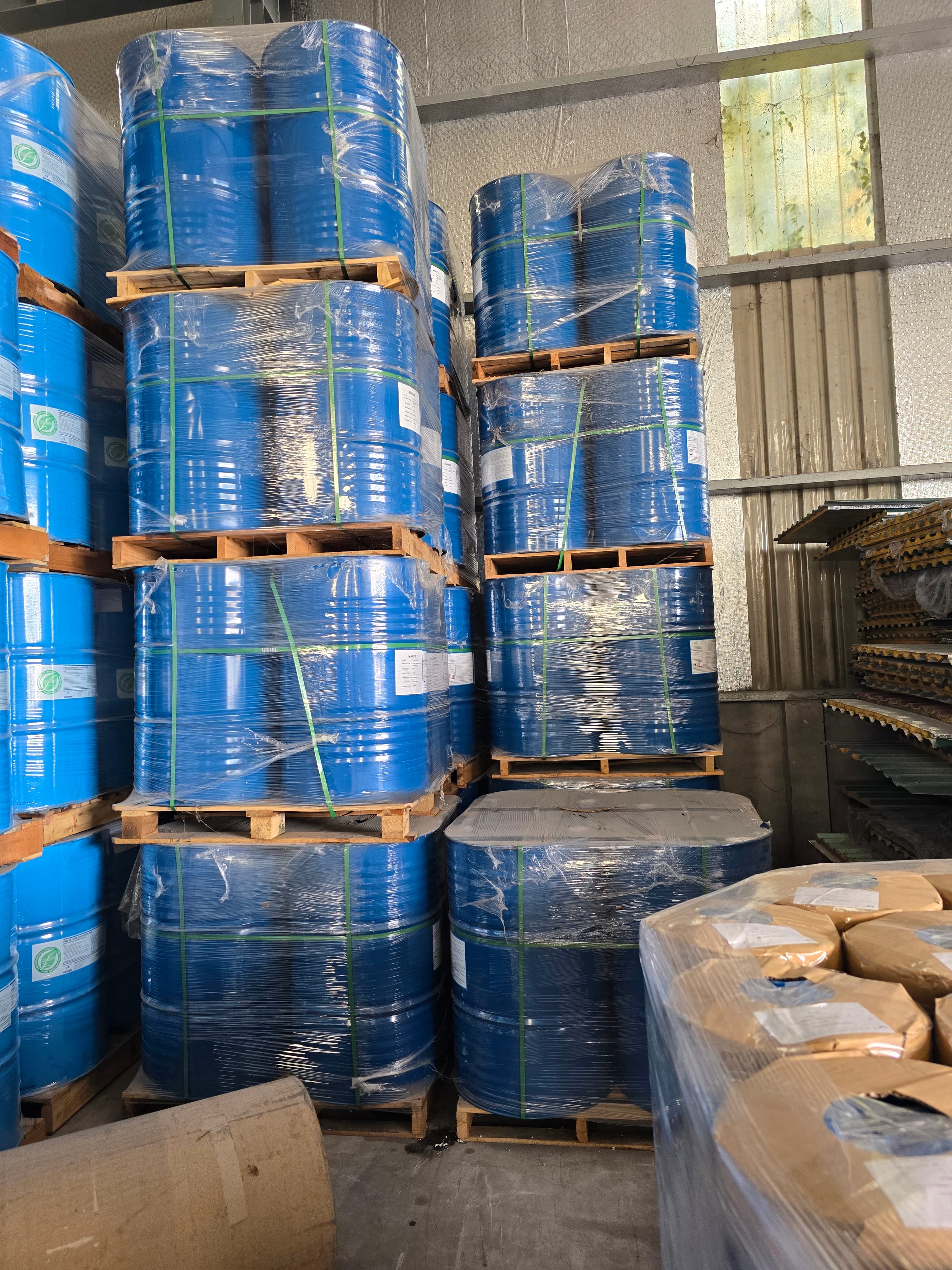 Blue polyol drums wrapped and stacked on wooden pallets